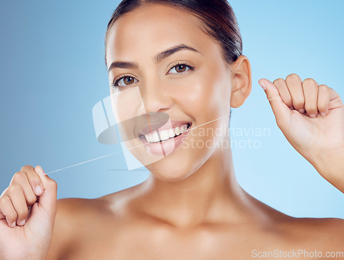 Image of Floss, teeth and portrait of woman in studio for beauty, healthy body and hygiene on blue background. Female model, tooth flossing and cleaning mouth for facial smile, fresh breath and happy dental