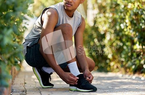 Image of Fitness, running and tying shoes of black man in nature and ready for cardio, jogging or workout. Training, exercise and health with runner and tie laces on ground for sports, wellness or motivation