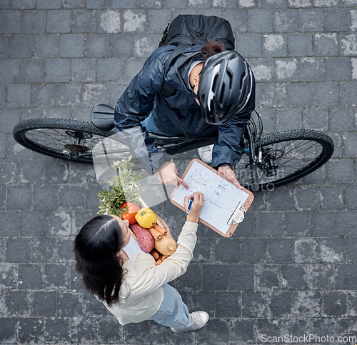 Image of Signature, courier and woman with grocery delivery, supermarket service and giving of food. Ecommerce, package and above of a customer signing a document for groceries from a retail worker in street