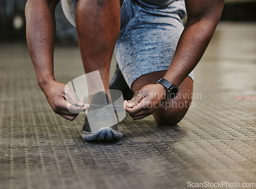 Image of Hands, fitness and tie shoes in gym to start workout, training or exercise for wellness. Sports, athlete health and black man tying sneakers or footwear laces to get ready for exercising or running.