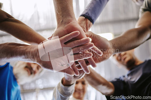 Image of Teamwork, hands together and low angle of people in gym for motivation, solidarity and team building. Collaboration exercise, group of friends or retired senior men and women huddle for workout goals