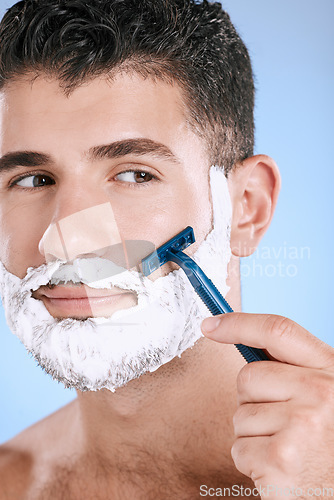 Image of Shaving, beard and cosmetic man with cream for grooming isolated on a blue background. Skincare, beauty and model with razor to shave hair on face with foam for a clean facial look on a backdrop