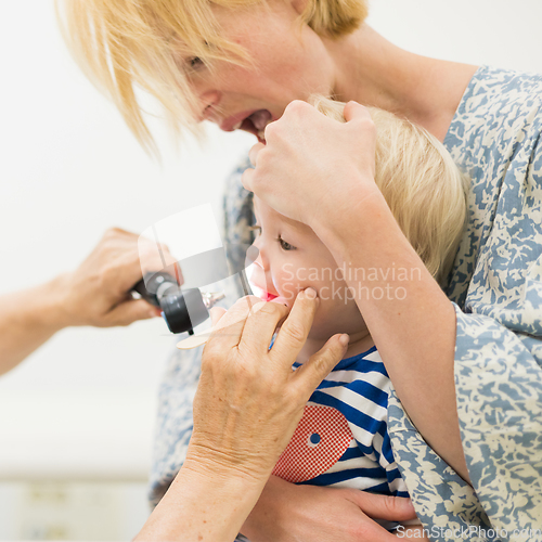 Image of Infant baby boy child being examined by his pediatrician doctor during a standard medical checkup in presence and comfort of his mother. National public health and childs care care koncept.