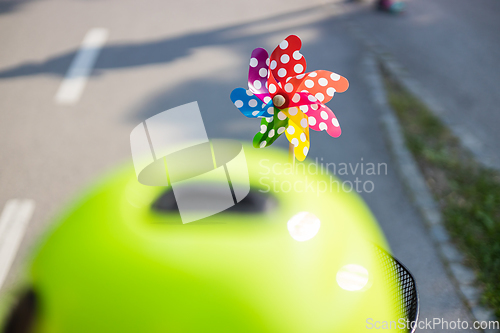 Image of Colorful pinwheel attached to bicycle basket to entertain toddler child riding on front child seat on bike in summer.