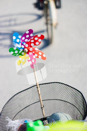 Image of Colorful pinwheel attached to bicycle basket to entertain toddler child riding on front child seat on bike in summer.