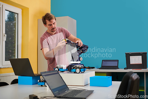 Image of A student testing his new invention of a robotic arm in the laboratory, showcasing the culmination of his research and technological prowess.