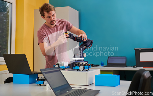 Image of A student testing his new invention of a robotic arm in the laboratory, showcasing the culmination of his research and technological prowess.