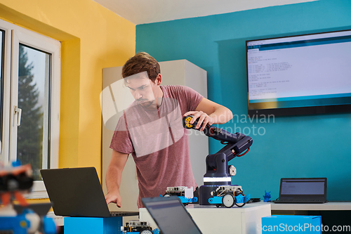 Image of A student testing his new invention of a robotic arm in the laboratory, showcasing the culmination of his research and technological prowess.