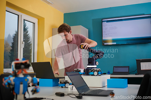 Image of A student testing his new invention of a robotic arm in the laboratory, showcasing the culmination of his research and technological prowess.