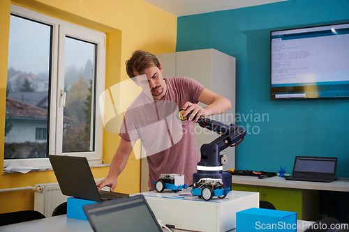 Image of A student testing his new invention of a robotic arm in the laboratory, showcasing the culmination of his research and technological prowess.