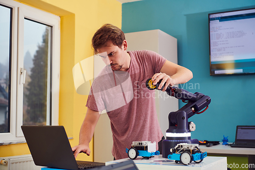 Image of A student testing his new invention of a robotic arm in the laboratory, showcasing the culmination of his research and technological prowess.