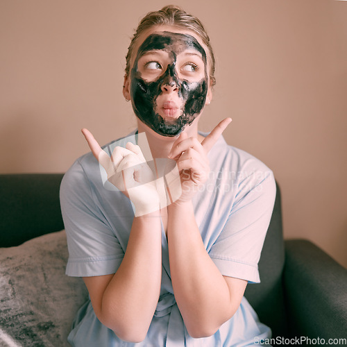 Image of Skincare, face mask and goofy woman in her house, home or apartment doing morning beauty routine with hand gesture. Portrait, relax and funny female doing facial for self care using charcoal