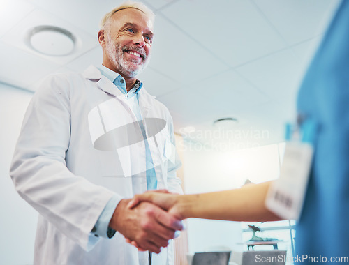 Image of Healthcare, handshake and doctor in partnership with a nurse for a consultation in the hospital. Happy, smile and senior medical worker shaking hands with colleague for agreement in a medicare clinic