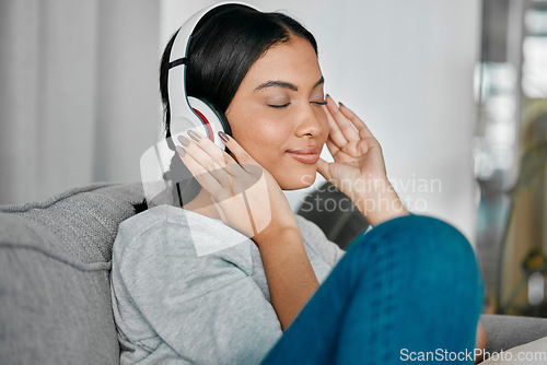 Image of Music, headphones and woman on sofa in home living room streaming radio or podcast. Relax, technology and female with headset for listening or enjoying song, audio or album on couch in house lounge.