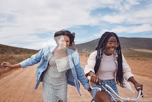 Image of Bike, girl friends and happy road trip fun of women outdoor on a desert path on summer vacation. Cycling, running and freedom of young people together with bicycle transportation feeling free