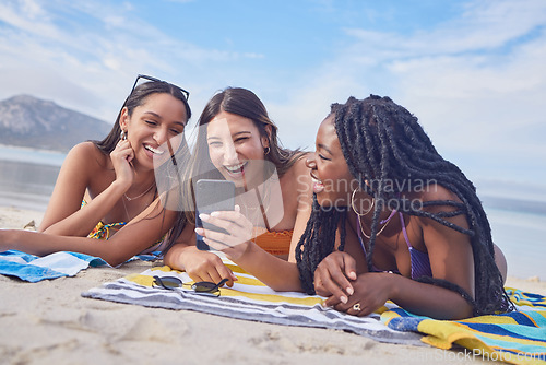 Image of Girl friends, ocean fun and phone of a teenager laughing at funny meme by the sea in Miami. Travel, vacation and sunshine with happy students enjoying spring break with mobile app lying on sand