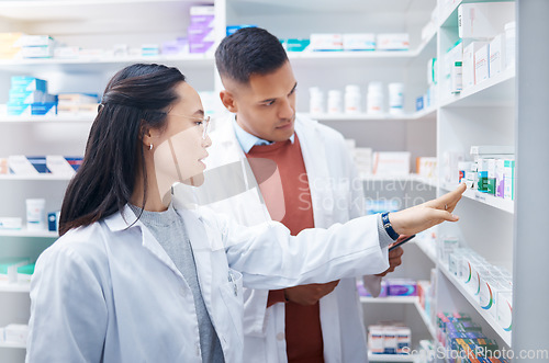 Image of Pharmacist, coworkers and conversation with pills, medicine and inventory for stock with discussion. Pharmacy, man or Asian woman with healthcare, prescriptions or coaching for new process or system