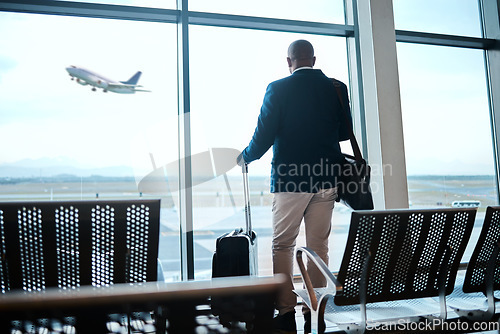 Image of Airport, suitcase and businessman waiting to board flight by the terminal for corporate work trip. Travel, luggage and professional male traveler watching flying plane by a window in terminus lounge.