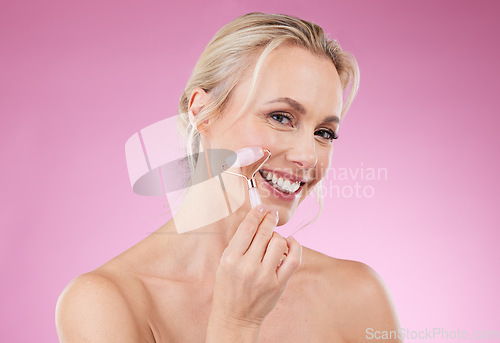 Image of Beauty, face roller and portrait of woman doing facial massage for dermatology and cosmetics. Happy aesthetic person on pink background for skincare, self care and rose quartz results for health glow