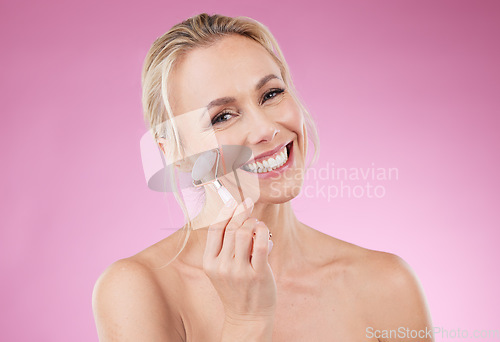 Image of Beauty, facial roller and woman portrait for face massage with dermatology and cosmetics in studio. Happy aesthetic person on pink background for skincare, self care and rose quartz results for glow