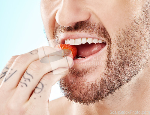 Image of Health, eating and strawberry with mouth of man for diet, detox and nutrition product. Wellness, smile and teeth with model and biting fruit closeup for vitamin c, glow and fiber in blue background