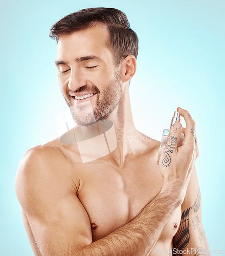 Image of Man, beauty and perfume spray in studio isolated on a blue background for wellness. Fragrance, cologne and happy male model with product for fresh scent, aroma and self care, hygiene and grooming.