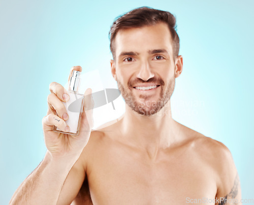 Image of Man, portrait and perfume bottle or product in studio isolated on a blue background for wellness. Fragrance, cologne and face of happy male model with parfum for fresh scent, aroma and self care.