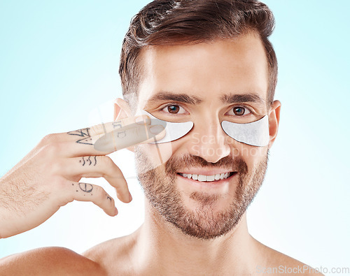 Image of Face, skincare and man with eye patches in studio isolated on a blue background. Beauty, portrait and male model with pad product for dermatology, cosmetics and facial treatment, wellness and health