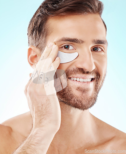 Image of Skincare, face and man with eye patch in studio isolated on a blue background. Beauty, portrait and male model with pad product for dermatology, cosmetics and facial treatment, wellness and health.