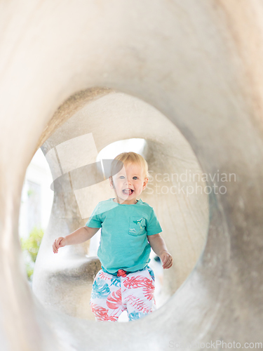 Image of Child playing on outdoor playground. Toddler plays on school or kindergarten yard. Active kid on stone sculpured slide. Healthy summer activity for children. Little boy climbing outdoors.