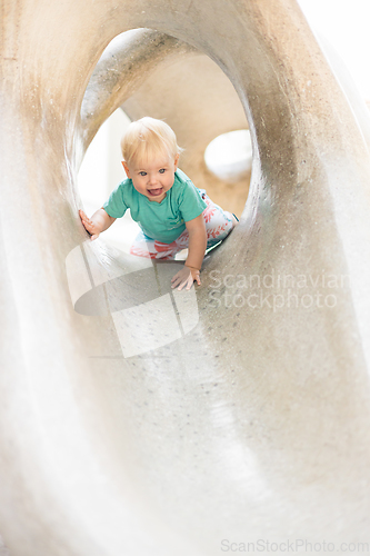 Image of Child playing on outdoor playground. Toddler plays on school or kindergarten yard. Active kid on stone sculpured slide. Healthy summer activity for children. Little boy climbing outdoors.