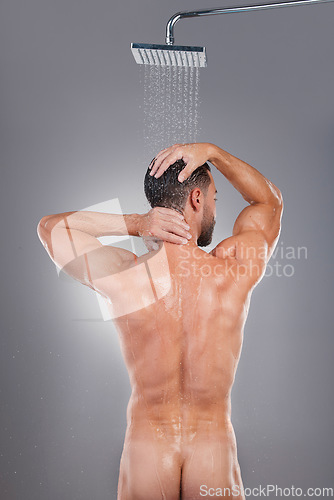 Image of Naked, routine and back of a man in the shower for health isolated on grey studio background. Morning, grooming and nude body of a person cleaning for shampoo, hygiene and washing with water