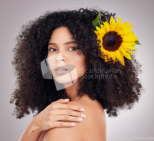Image of Portrait, serious or face of black woman with sunflower in hair in studio for spring time, luxury spa or self care. Aesthetic, beauty facial or girl model with plant for skincare, cosmetic or makeup