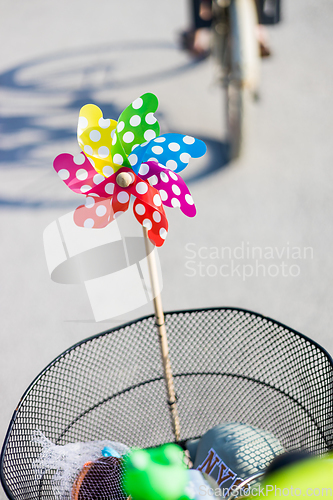 Image of Colorful pinwheel attached to bicycle basket to entertain toddler child riding on front child seat on bike in summer.