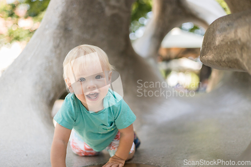 Image of Child playing on outdoor playground. Toddler plays on school or kindergarten yard. Active kid on stone sculpured slide. Healthy summer activity for children. Little boy climbing outdoors.