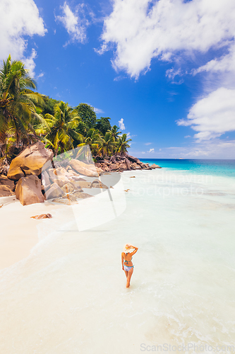 Image of Woman enjoying Anse Patates picture perfect beach on La Digue Island, Seychelles.