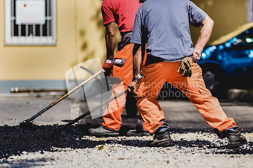 Image of Asphalt surfacing manual labor.