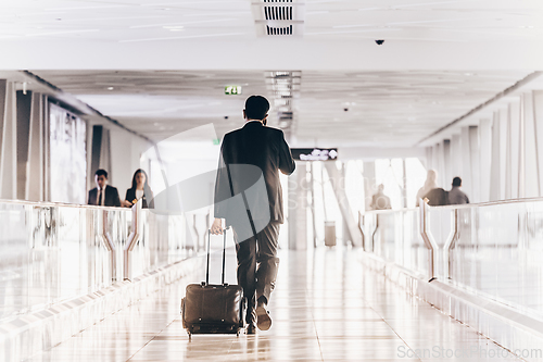 Image of Businessman at airport corridor walking to departure gates.