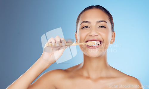 Image of Bamboo toothbrush, toothpaste and portrait of woman for dental wellness, healthy cleaning or model cosmetics. Happy female teeth, eco wooden brush and mouth for smile, face and studio blue background