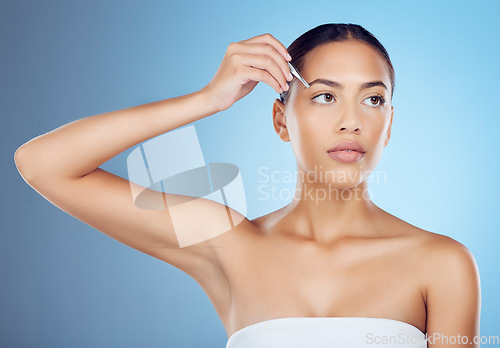 Image of Tweezers, eyebrow and woman in studio for beauty, grooming and hygiene on blue background space. Hair removal, epilation and brow tool by girl skin model relax with luxury, product and cosmetic care