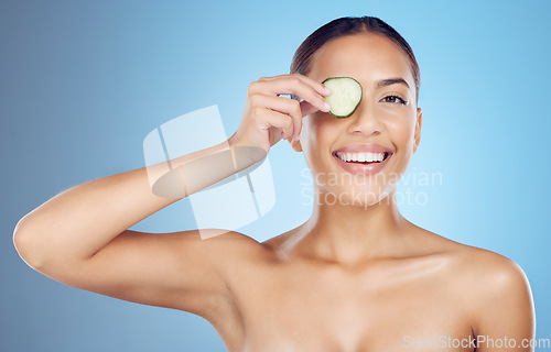 Image of Cucumber, woman and portrait face for beauty, clean wellness diet and blue studio background. Happy model, eyes and green fruits cosmetics for detox, facial skincare and healthy aesthetic benefits