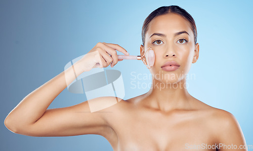 Image of Woman, portrait and face massage with roller, facial product and aesthetic skincare in studio. Young model, crystal stone treatment and wellness for natural cosmetics, rose quartz dermatology and spa