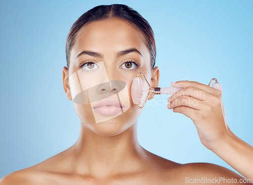 Image of Woman, portrait and face roller for beauty, facial product and aesthetic skincare in studio. Young model, crystal stone treatment and wellness for natural cosmetics, rose quartz dermatology and salon