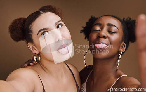 Image of Beauty, friends and tongue with selfie of black women for social media, skincare and fashion. Happy, silly and picture with funny face of girl for internet, comic and crazy in brown background studio