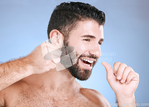 Image of Oral, floss and dental hygiene with a man in studio on a blue background cleaning his teeth for healthy gums. Dentist, healthcare and mouth with a young male flossing to remove plaque or gingivitis