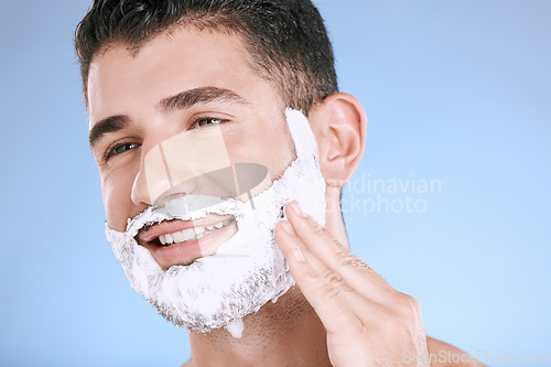 Image of Facial, foam on beard and man with smile and hand on face with product placement and mockup in studio. Shaving cream, hair and skincare for happy male model grooming, isolated on blue background.