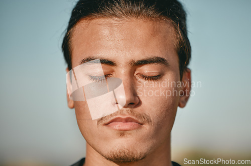 Image of Zen, meditation and face of man meditating closed eyes outdoors for calm, peace and is mindful with blue sky background. Person, relax and spiritual male with faith in wellness and health