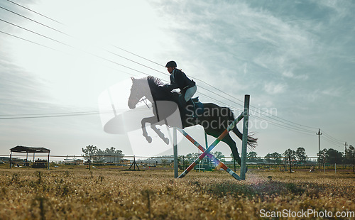 Image of Woman on horse, jumping and equestrian sports practice for competition with blue cloudy sky on ranch. Training jump, jockey or rider on animal for racing on obstacle course, dressage or hurdle race.