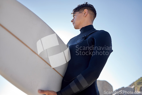 Image of Surfing, beach and man with blue sky outdoor for water sports, training and exercise. Surfboard, morning workout and sea with summer sun and young surfer ready for sport and freedom at the ocean