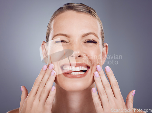 Image of Skincare, comic and portrait of a woman touching face isolated on a grey studio background. Funny, makeup and a model for cosmetics, beauty expression and crazy on a backdrop with tongue out